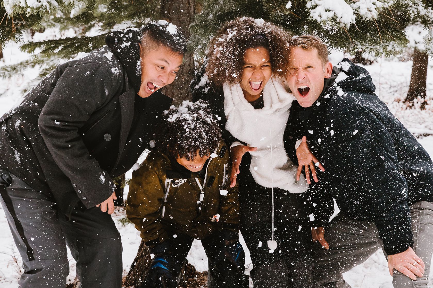 Four person family playing in snow.
