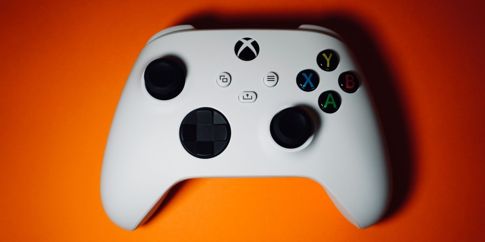 Photo of a white Xbox Series X and S controller against an orange background.
