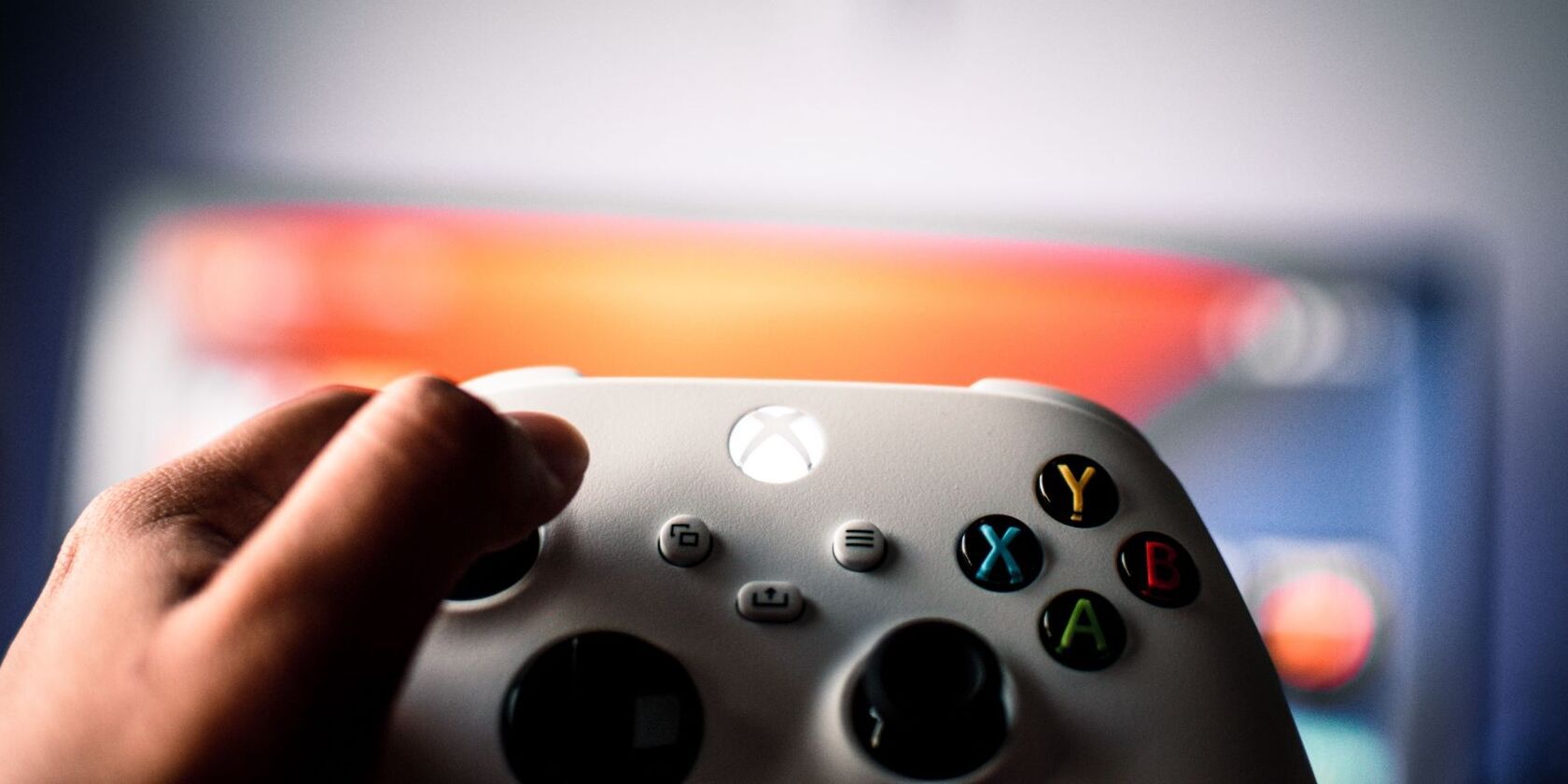 Foto pengontrol Xbox Series X atau S putih yang dipegang di depan televisi 