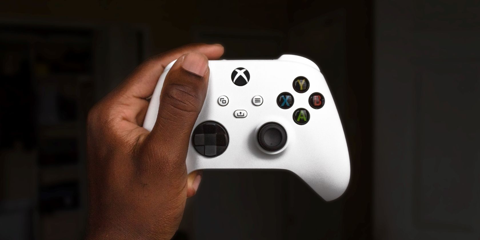 A photograph of a man holding up a white Xbox controller 
