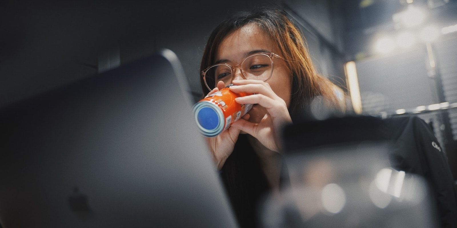 Woman Happily Drinking Soda in Front of Her Laptop