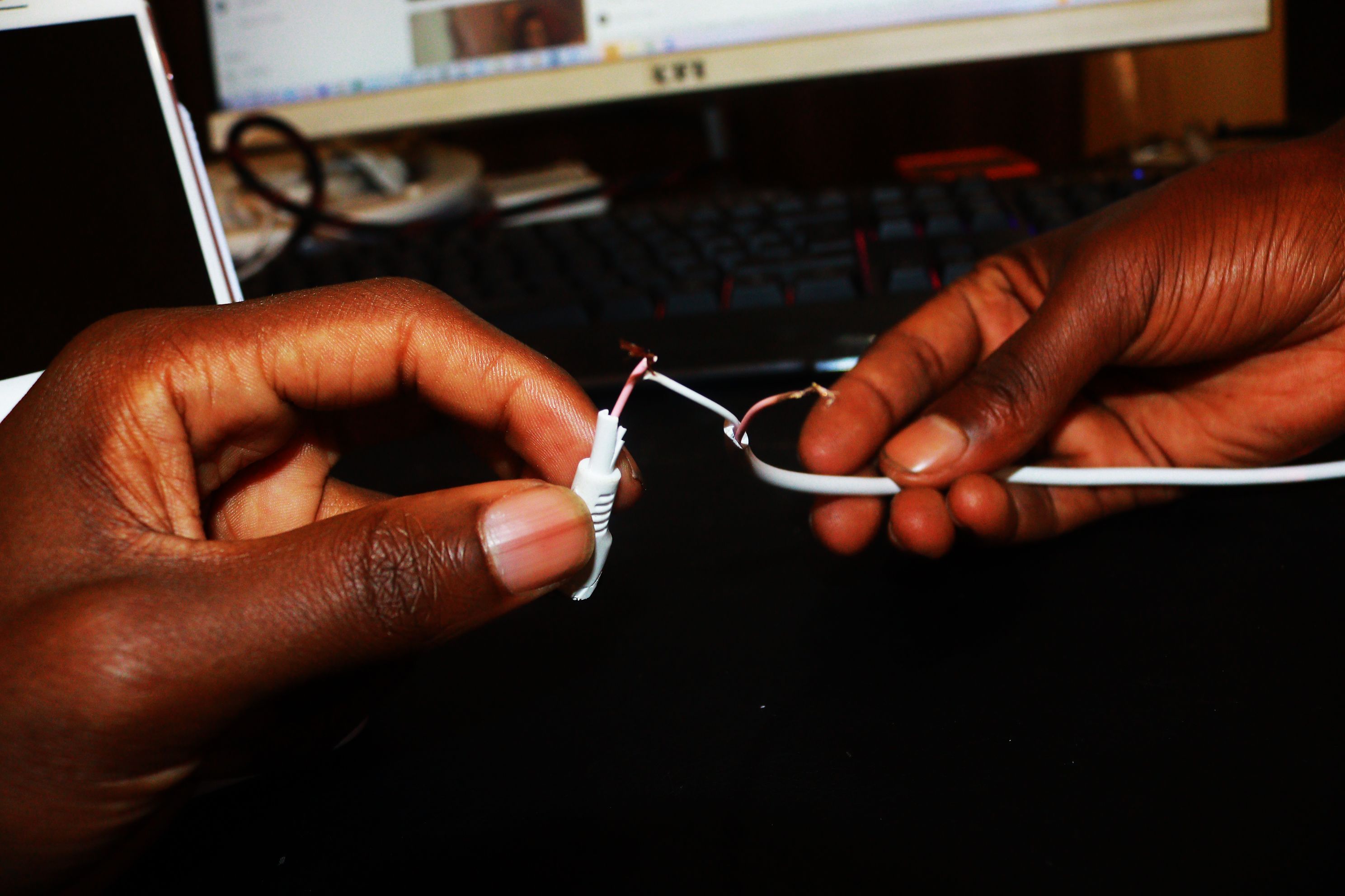Hands holding two wires before the soldering process