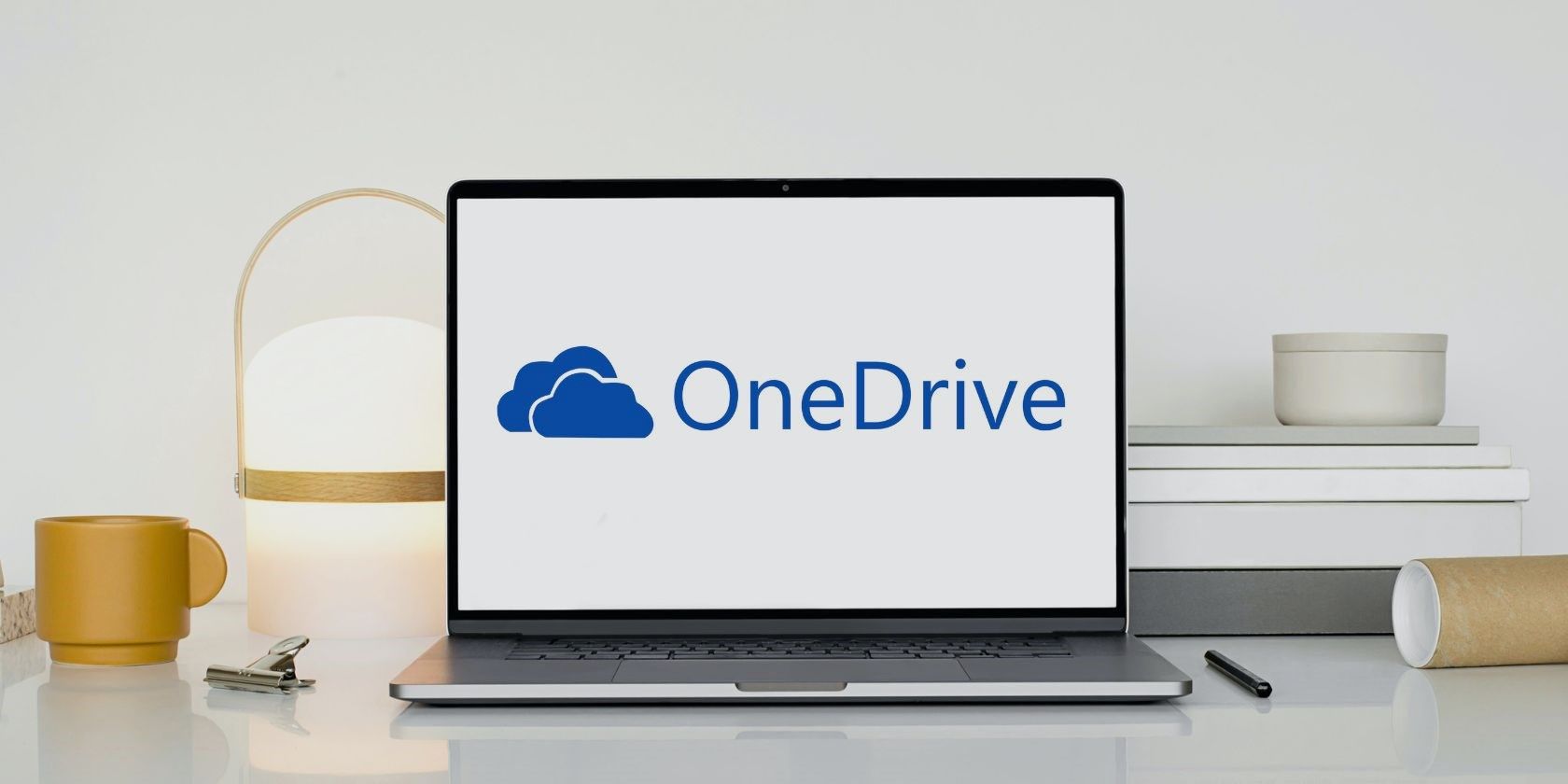 Laptop con el logo de OneDrive en una mesa de madera blanca