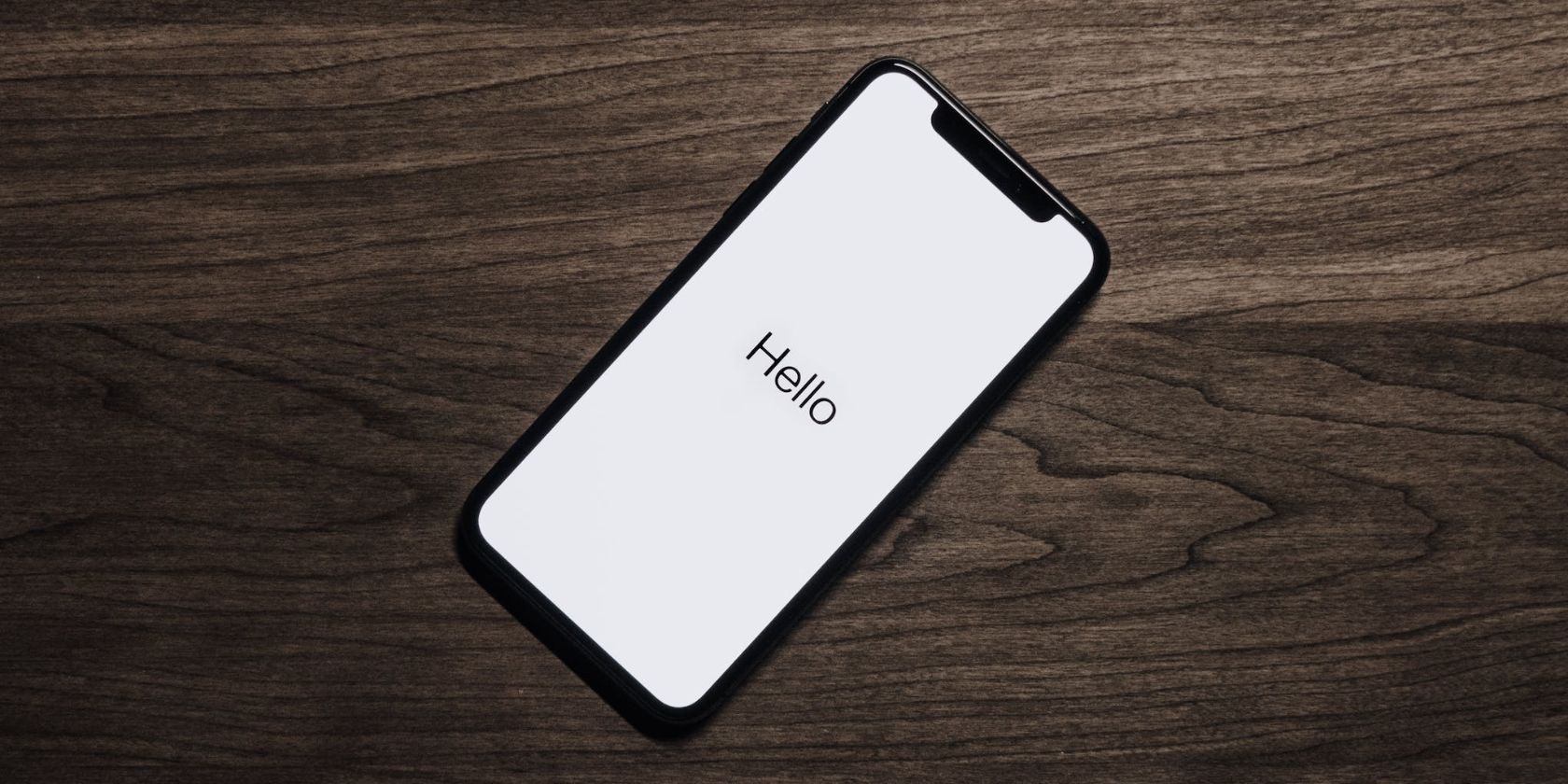 iphone on wooden surface showing white hello screen 