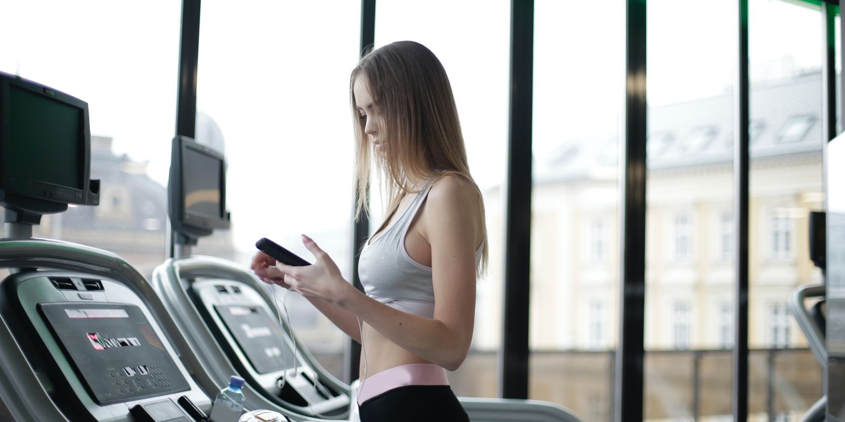 A woman using her phone on a treadmill.