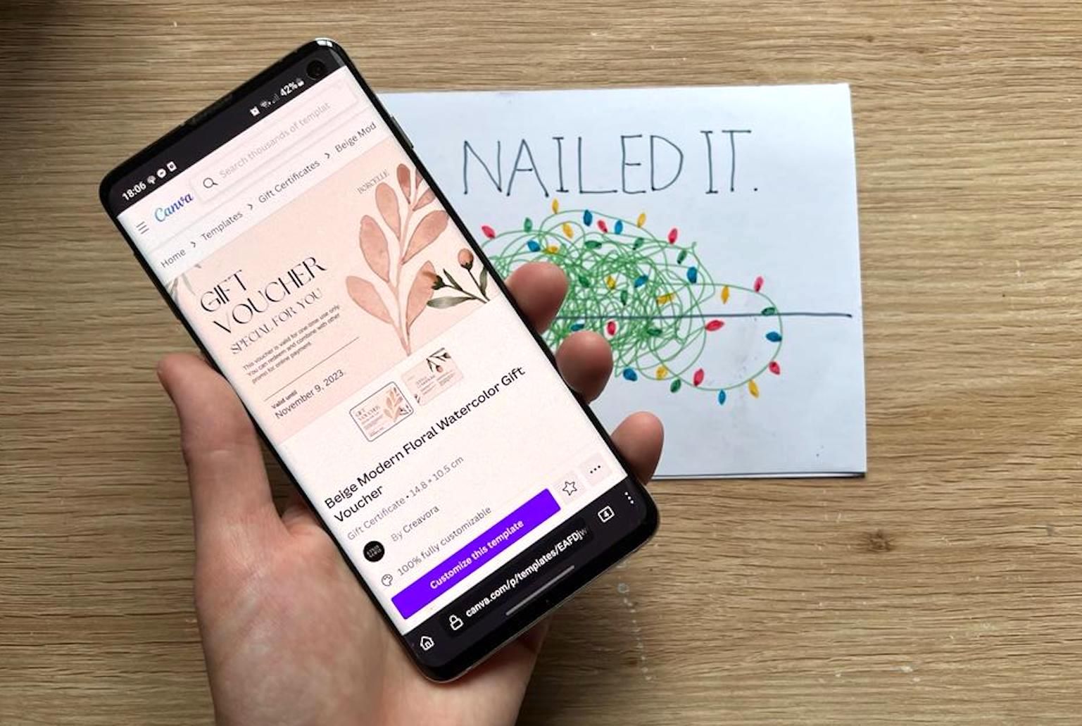 A phone above a Christmas card with a gift voucher on screen