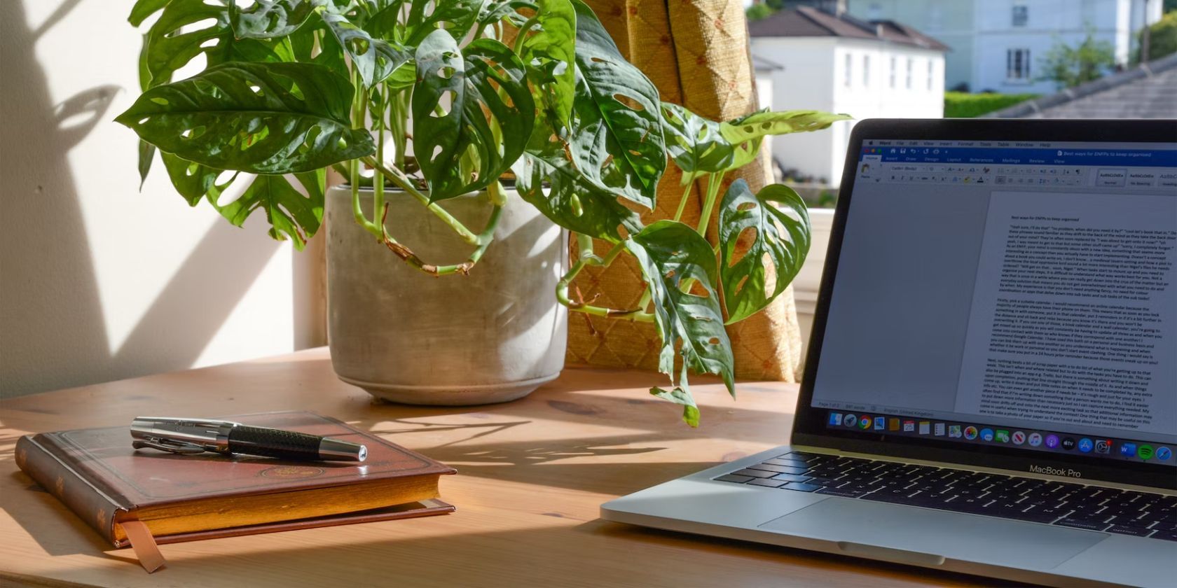 open laptop on desk with journal and house plant