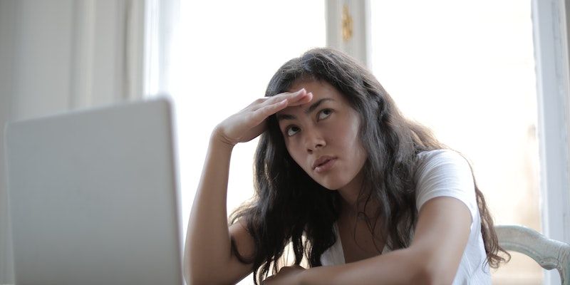An annoyed woman looking away from her laptop