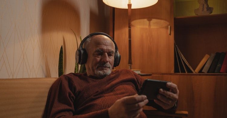 Elderly man watching something on the tablet with headphones