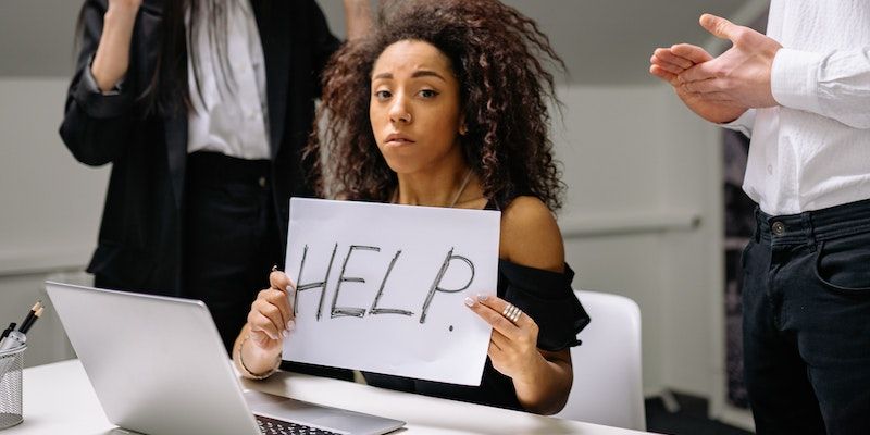 A woman holding a help sign at work
