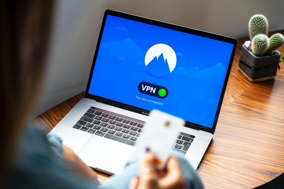 A person holding a credit card with a VPN connected on a laptop