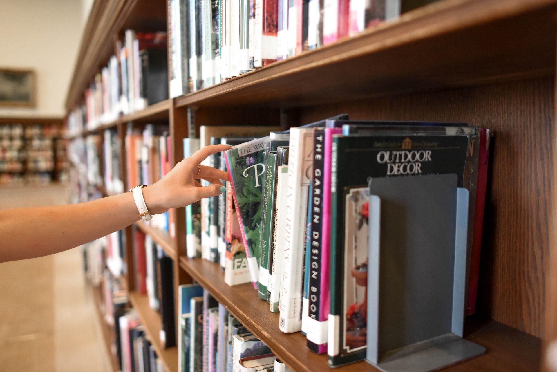 Reader taking library book from shelf