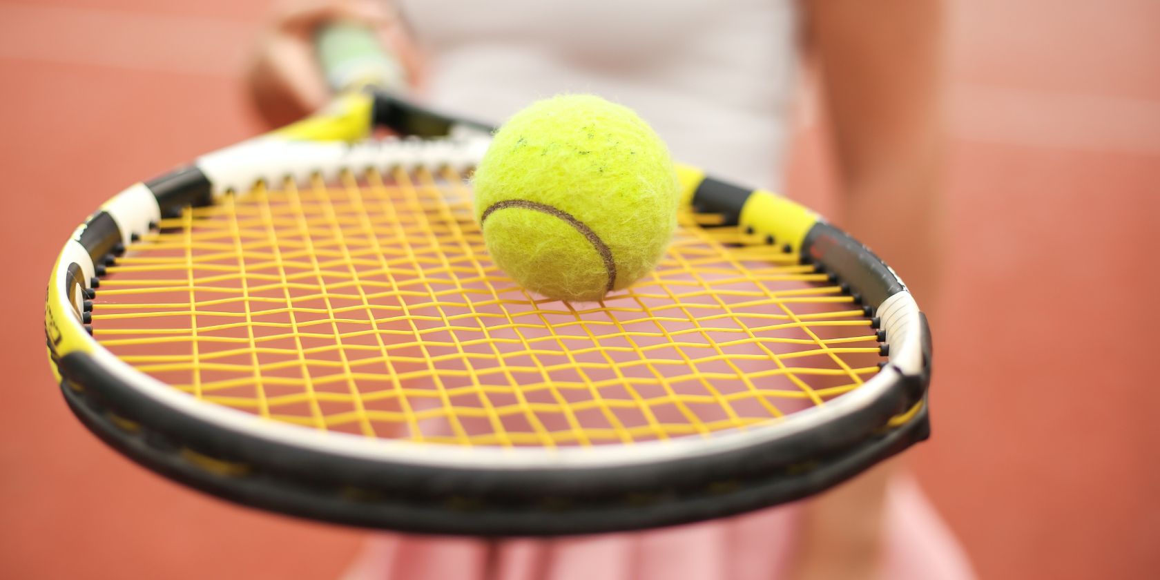 Two tennis balls balancing on tennis racquet