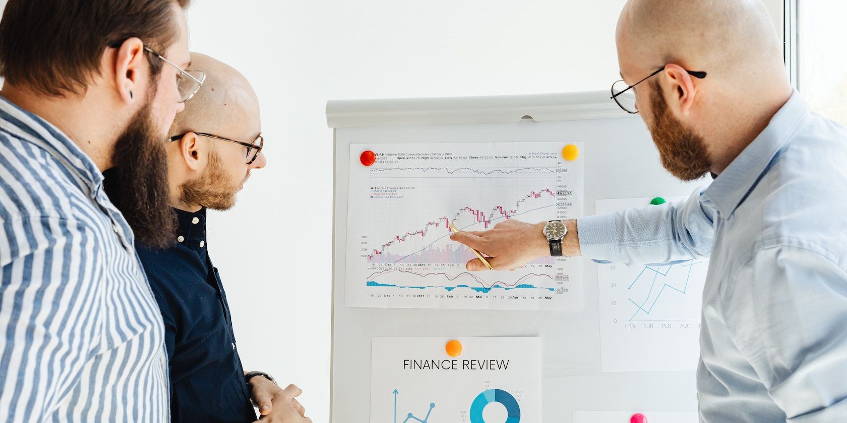 Three men analyzing a graph on the wall