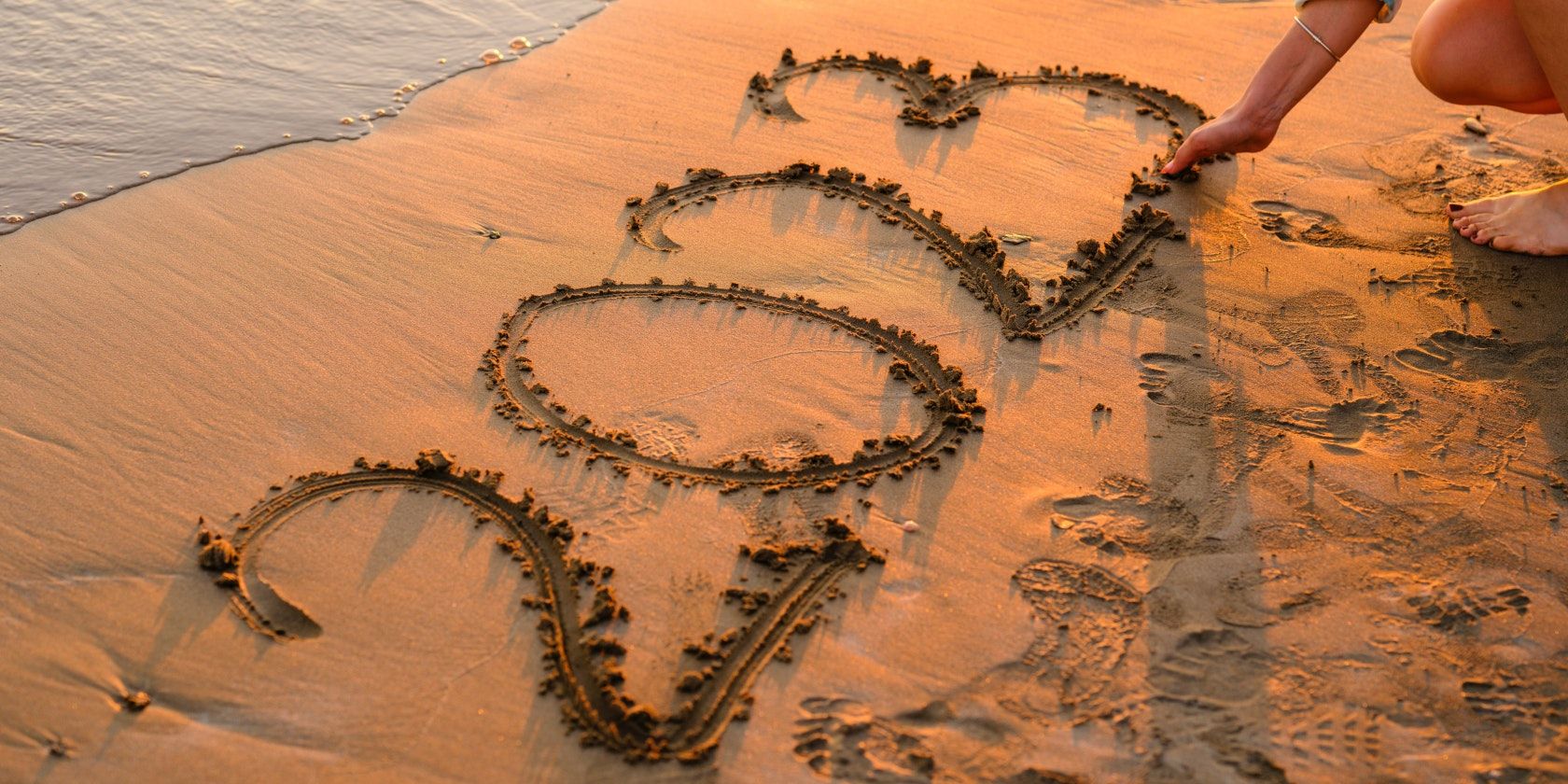 Woman drawing 2023 in sand at beach