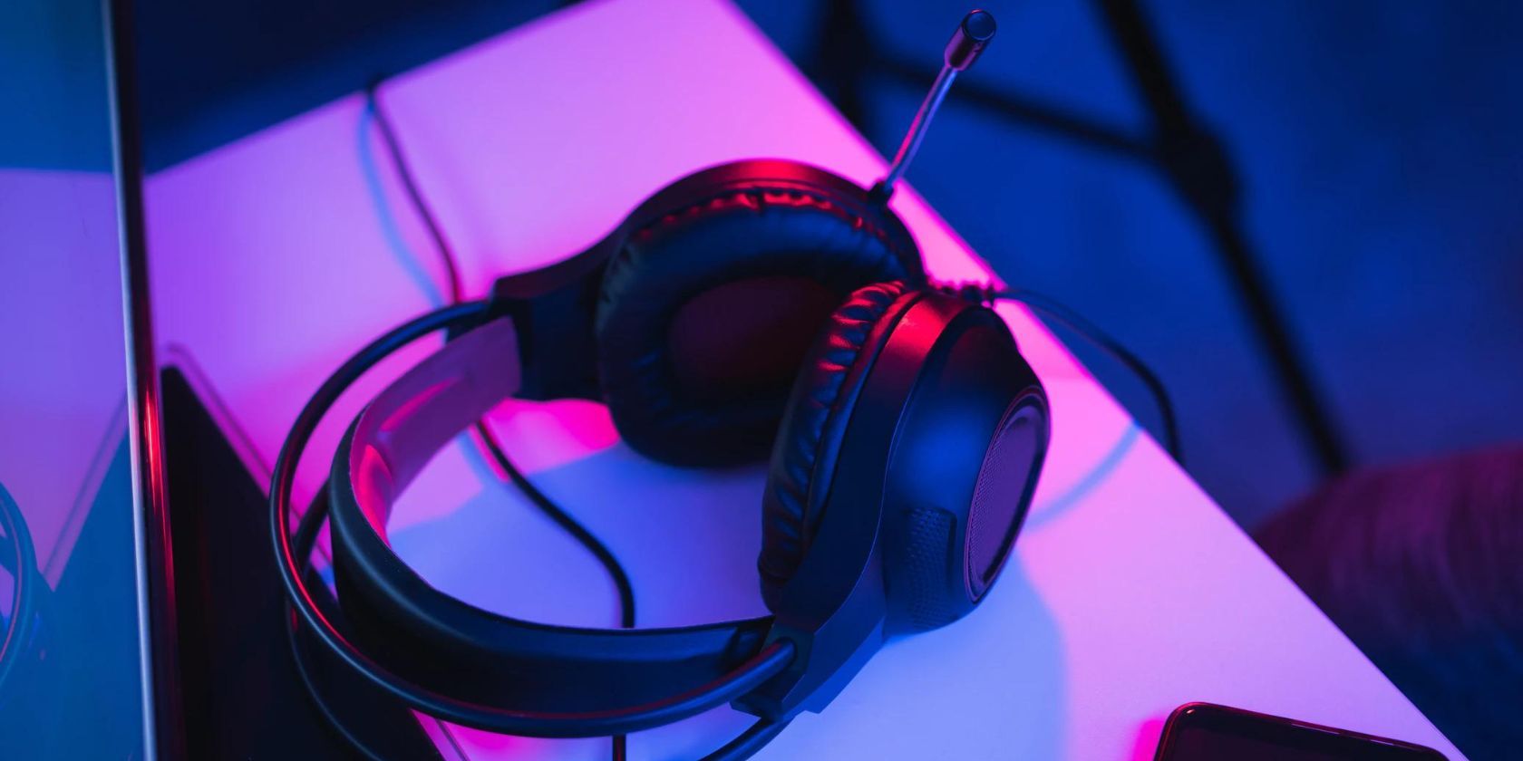 A gaming headset sitting on a table with purple RGB lights