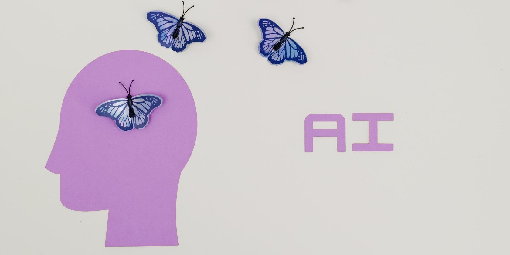 Side profile head silhouette with three AI butterflies flying out of it and 'AI' printed to the right