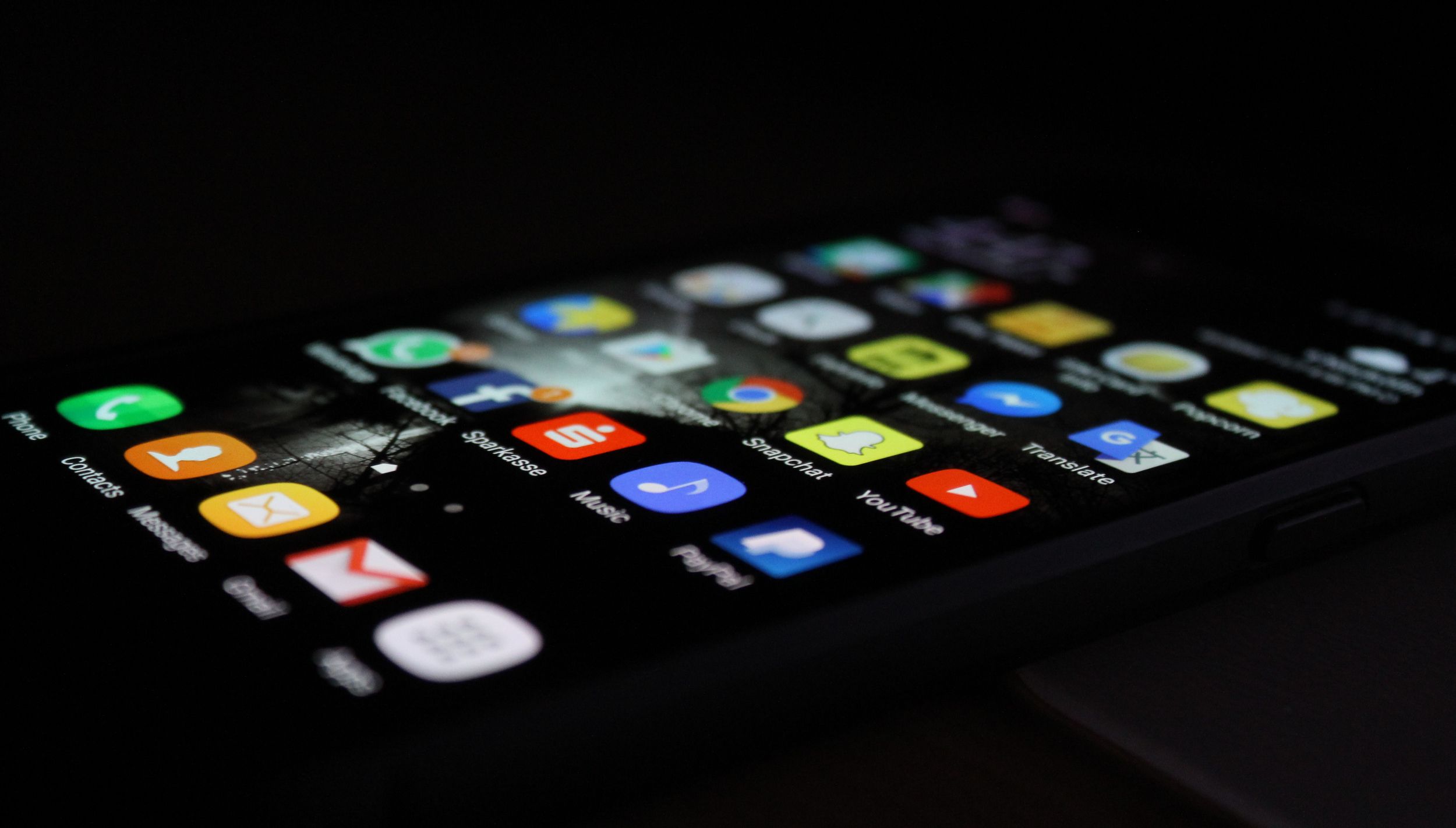phone in dark room with app menu on screen