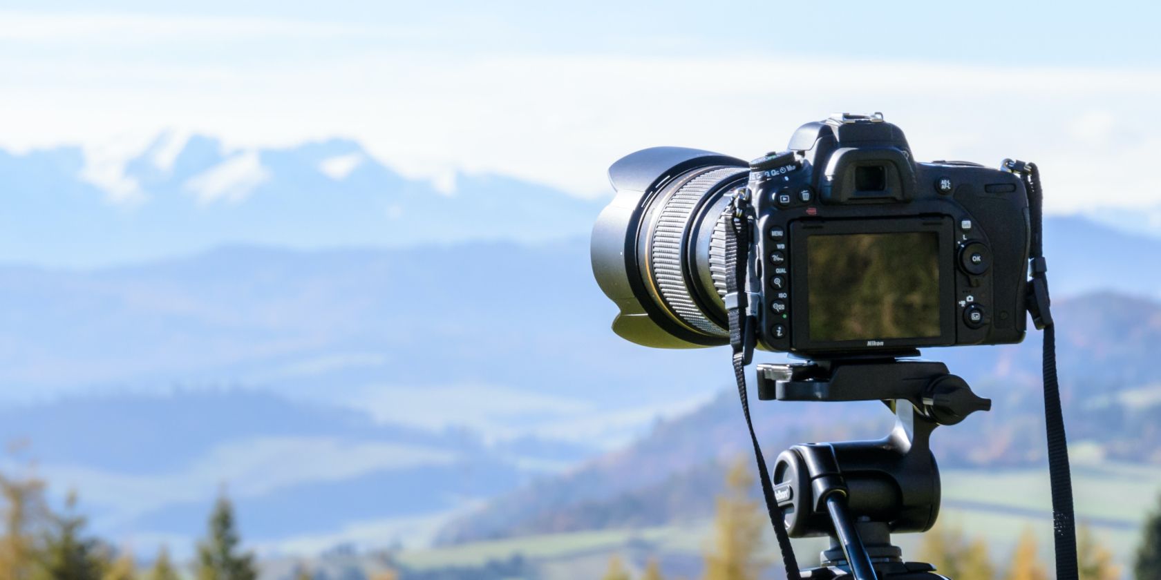 Camera mounted on tripod with mountains in background