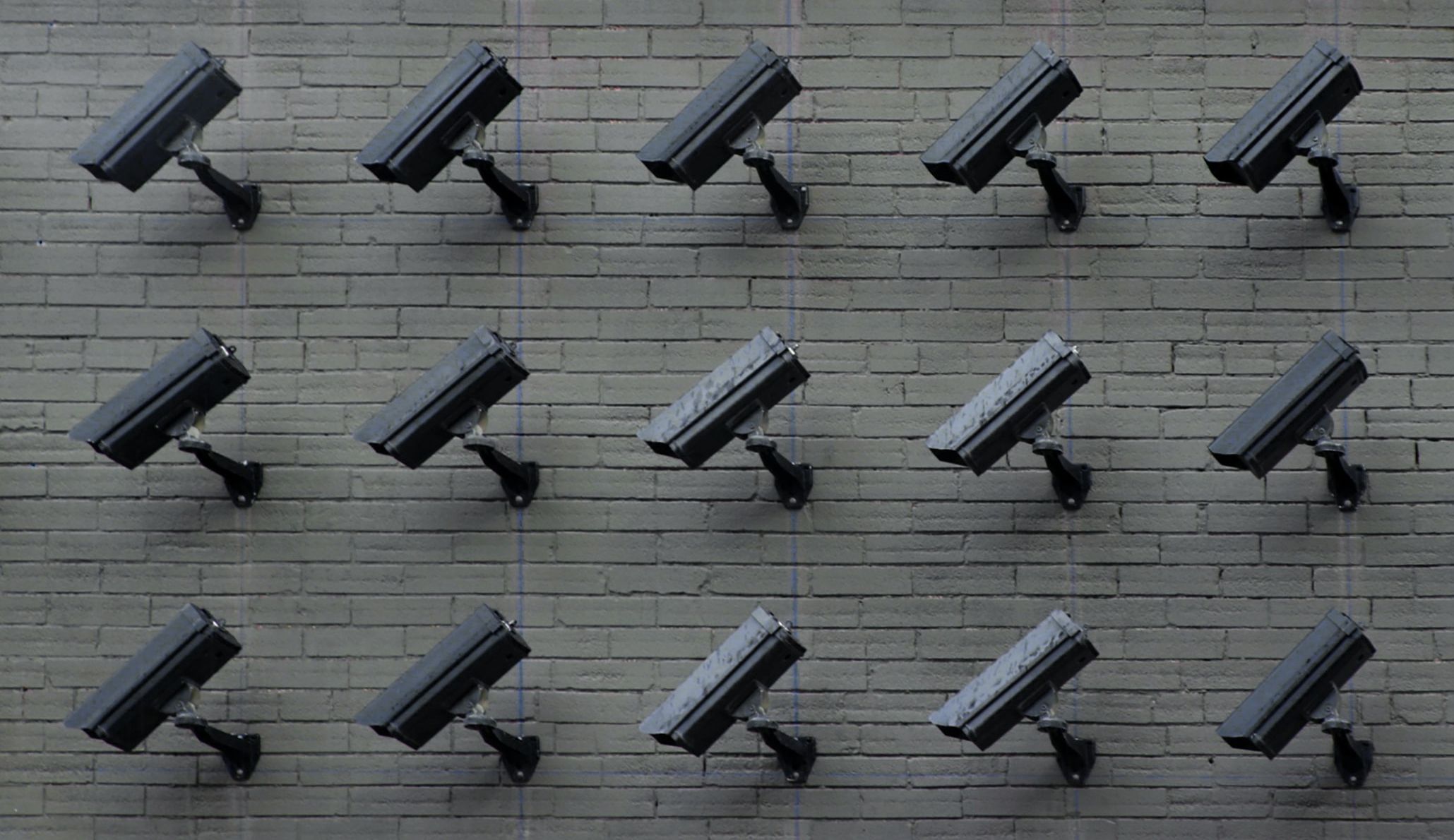 wall filled with black cctv cameras facing downward
