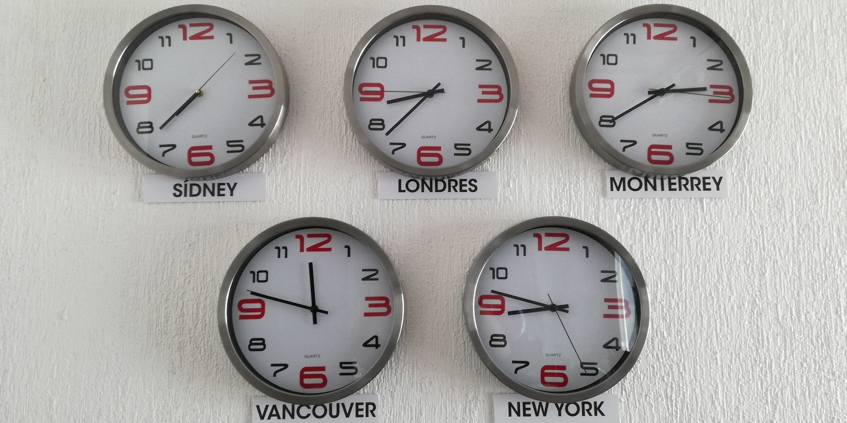 Five wall clocks showing times from different cities around the world. 