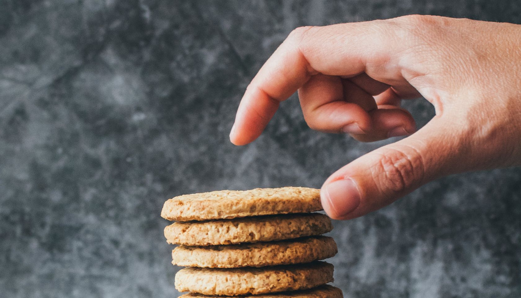 A man's hand reaches for a stack of cookies