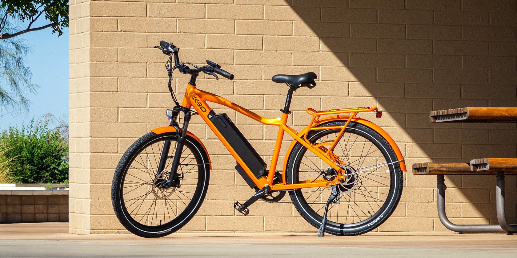an orange and black e-bike parked near a bench