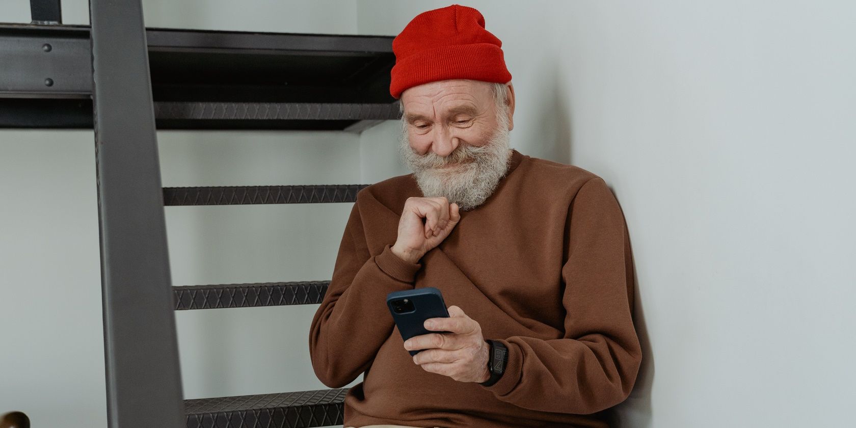 Image of an elder man looking at a phone one-handed