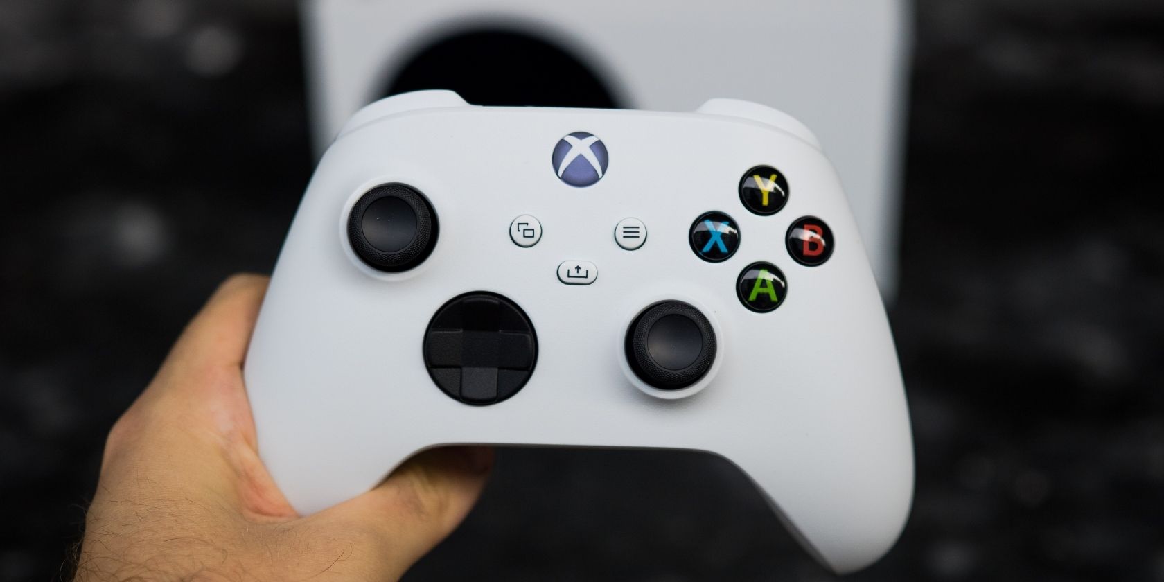 A photo of an Xbox Series S controller being held above an Xbox Series S console