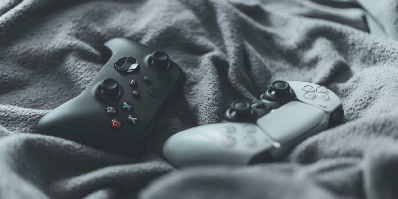 A photograph of a black Xbox Series X controller next to a standard PlayStation 5 controller 