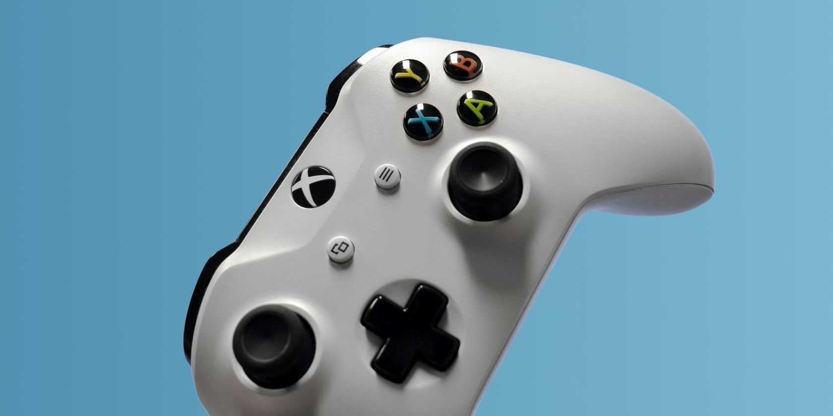A photograph of a white Xbox One controller in front of a blue background 