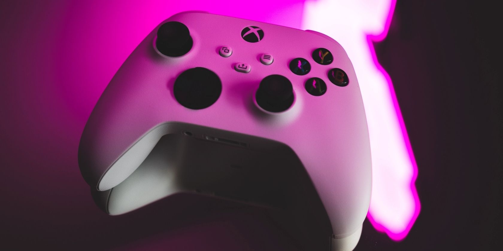 A photo of a white Xbox Series X and Series S compatible Xbox controller lit by a luminous pink light