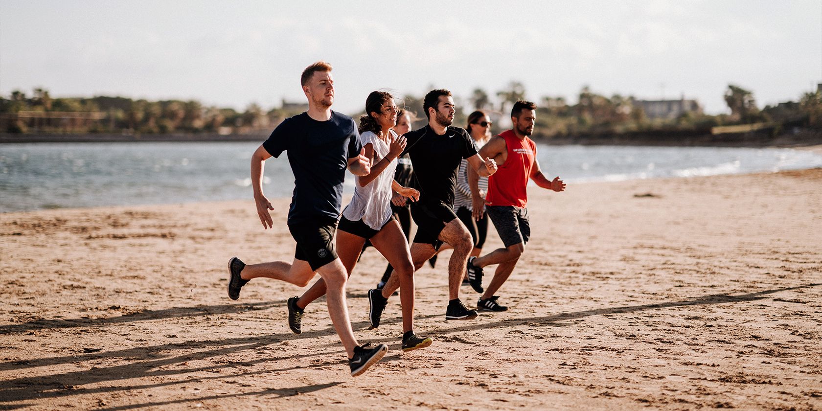 pessoas correndo na praia juntas em grupo
