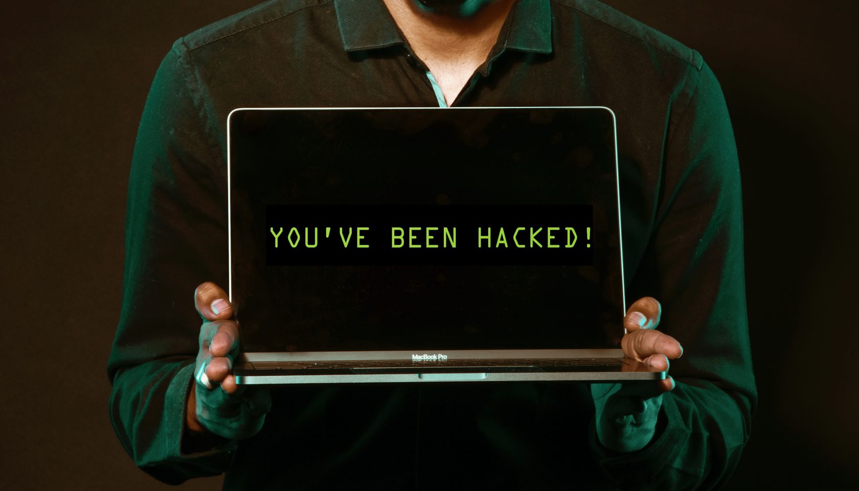 Man holding a laptop that says you have been hacked
