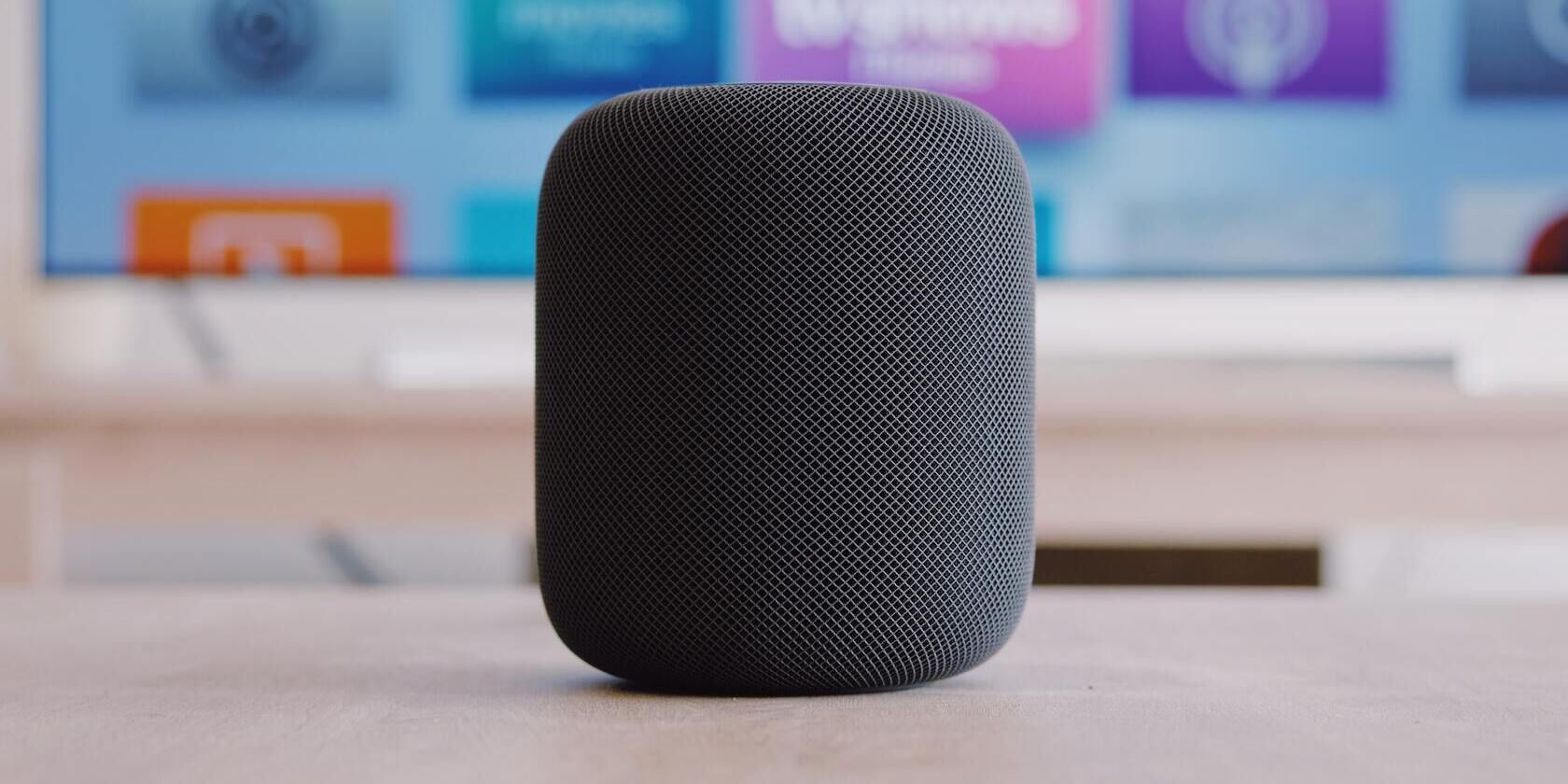 Black HomePod on a table in front of a TV