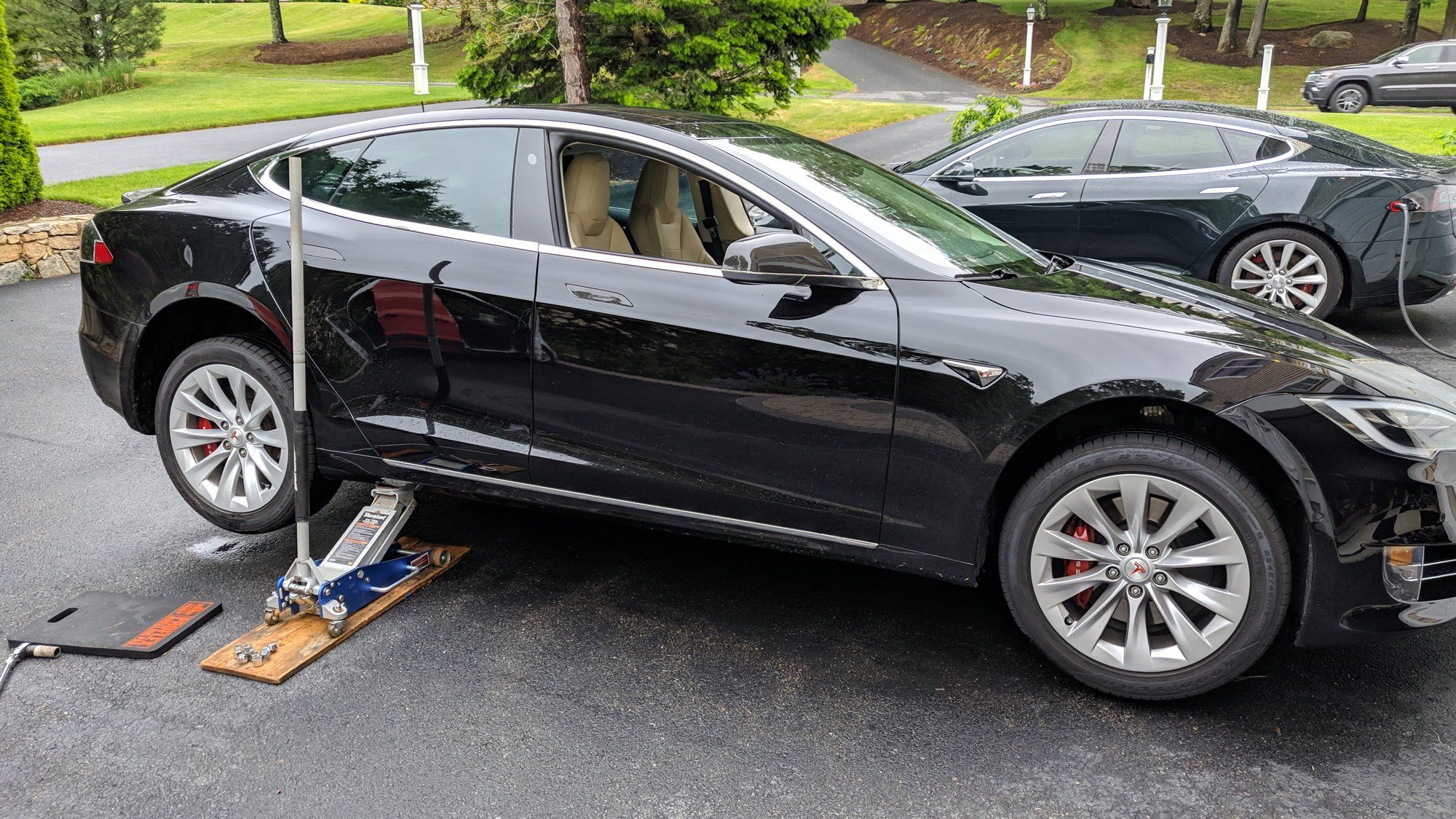 Une Tesla Model S noire sur un cric dans une allée.