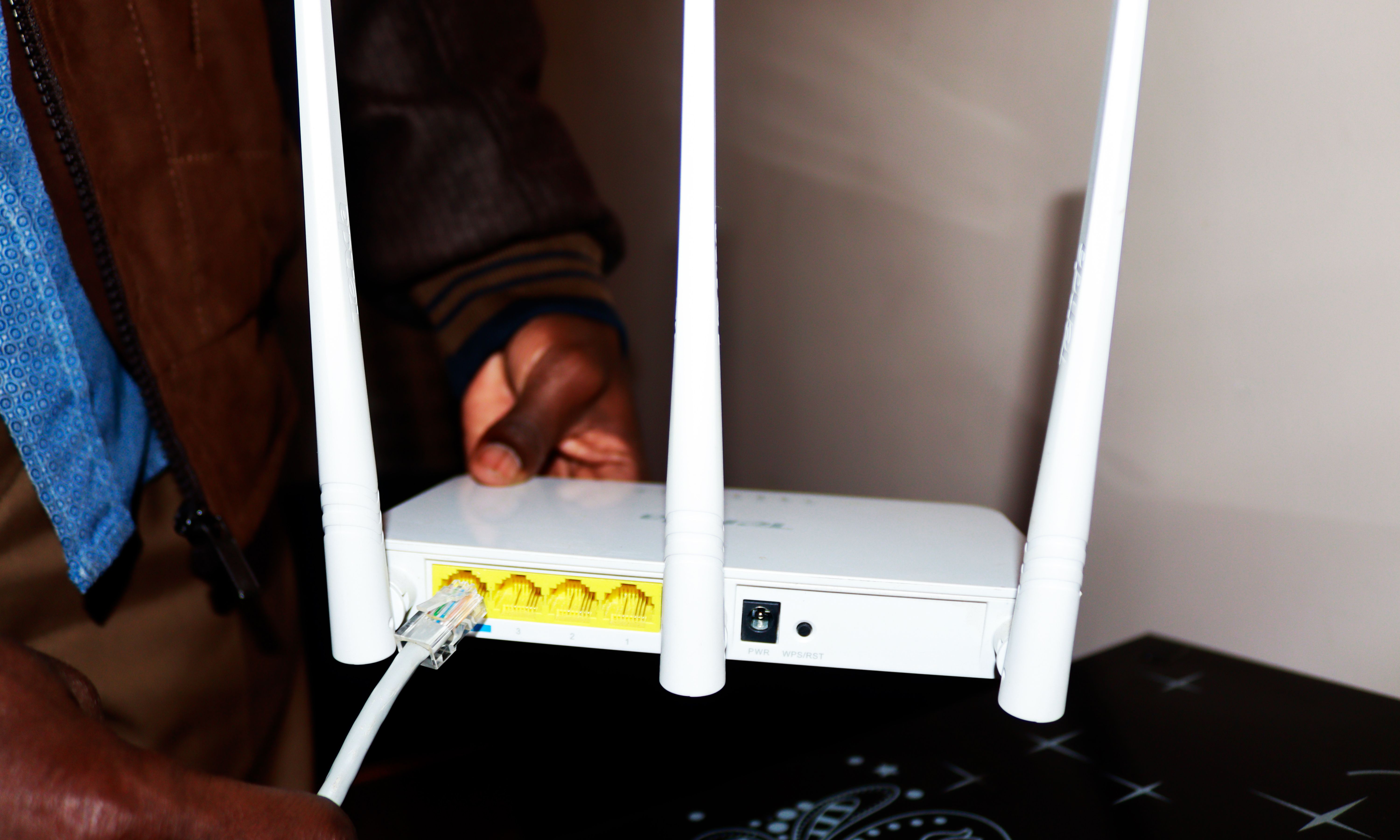 A person connecting an Ethernet cable into Wi-Fi router