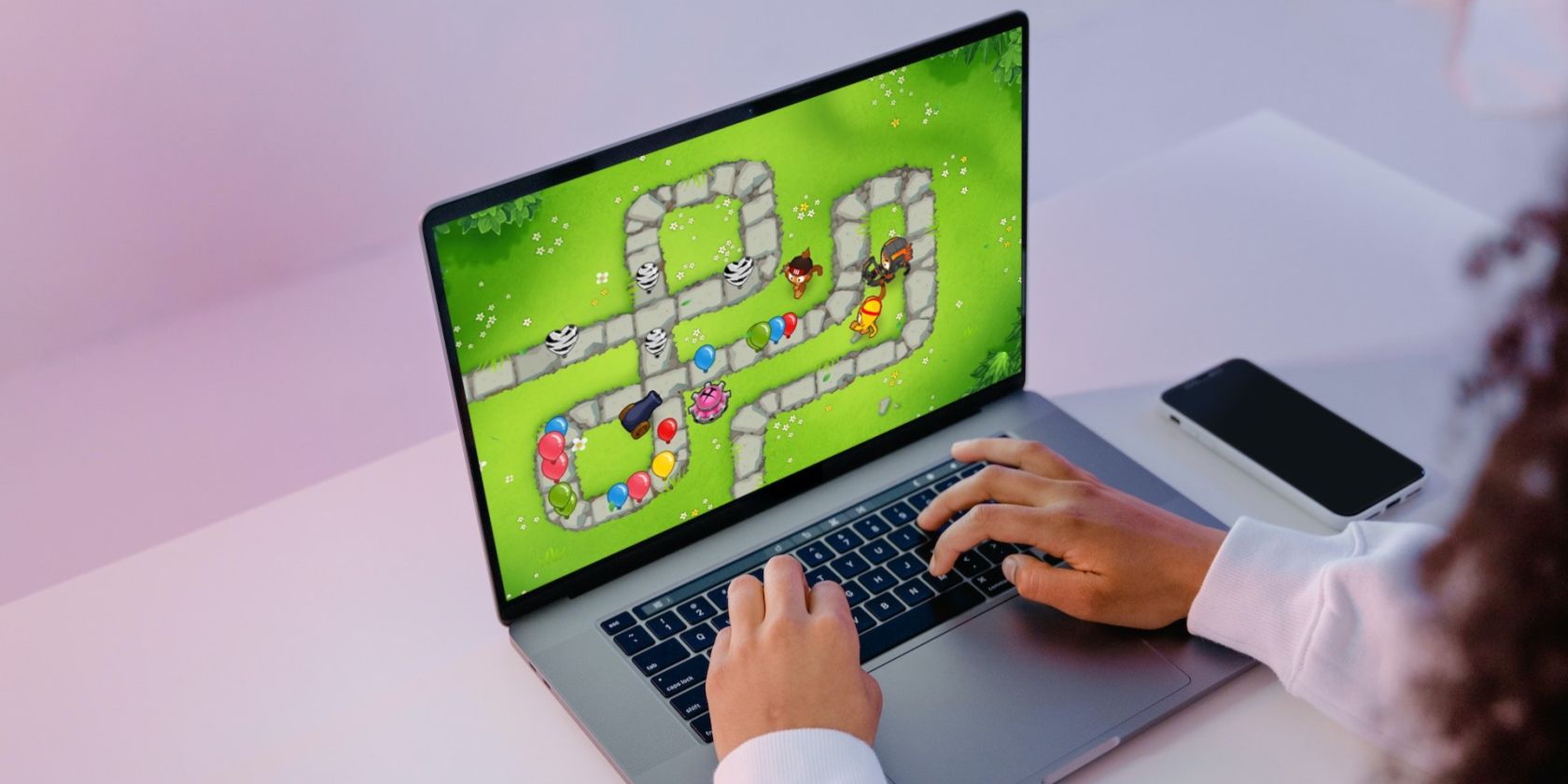 Kid playing Bloons TD6 on a MacBook