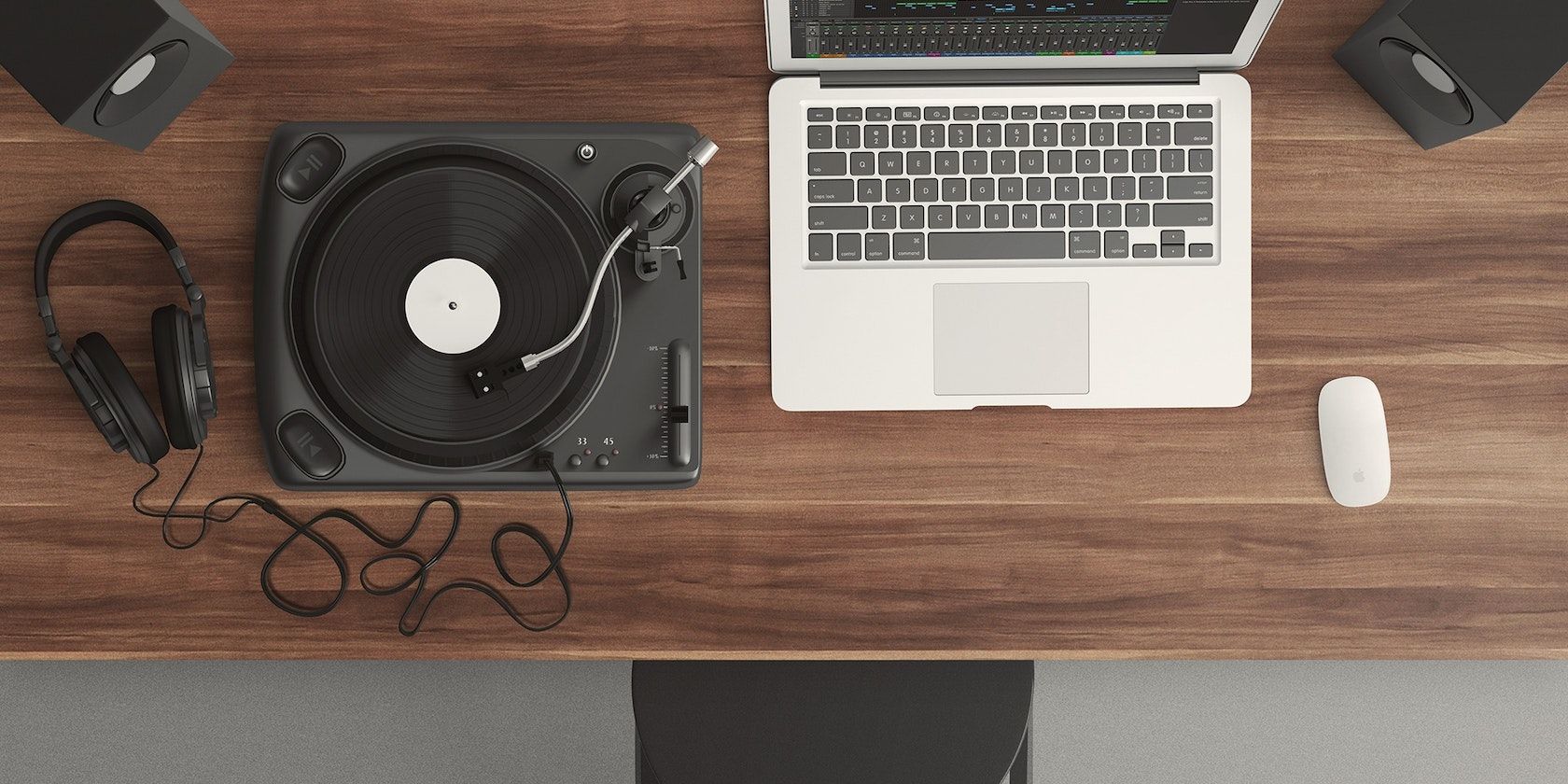 MacBook on a table with a record player, speakers, and headphones