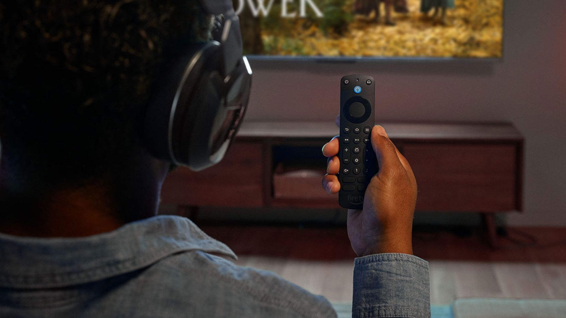 Man sitting infront of tv wearing headphones while holding an Amazon Fire TV Stick remote-1
