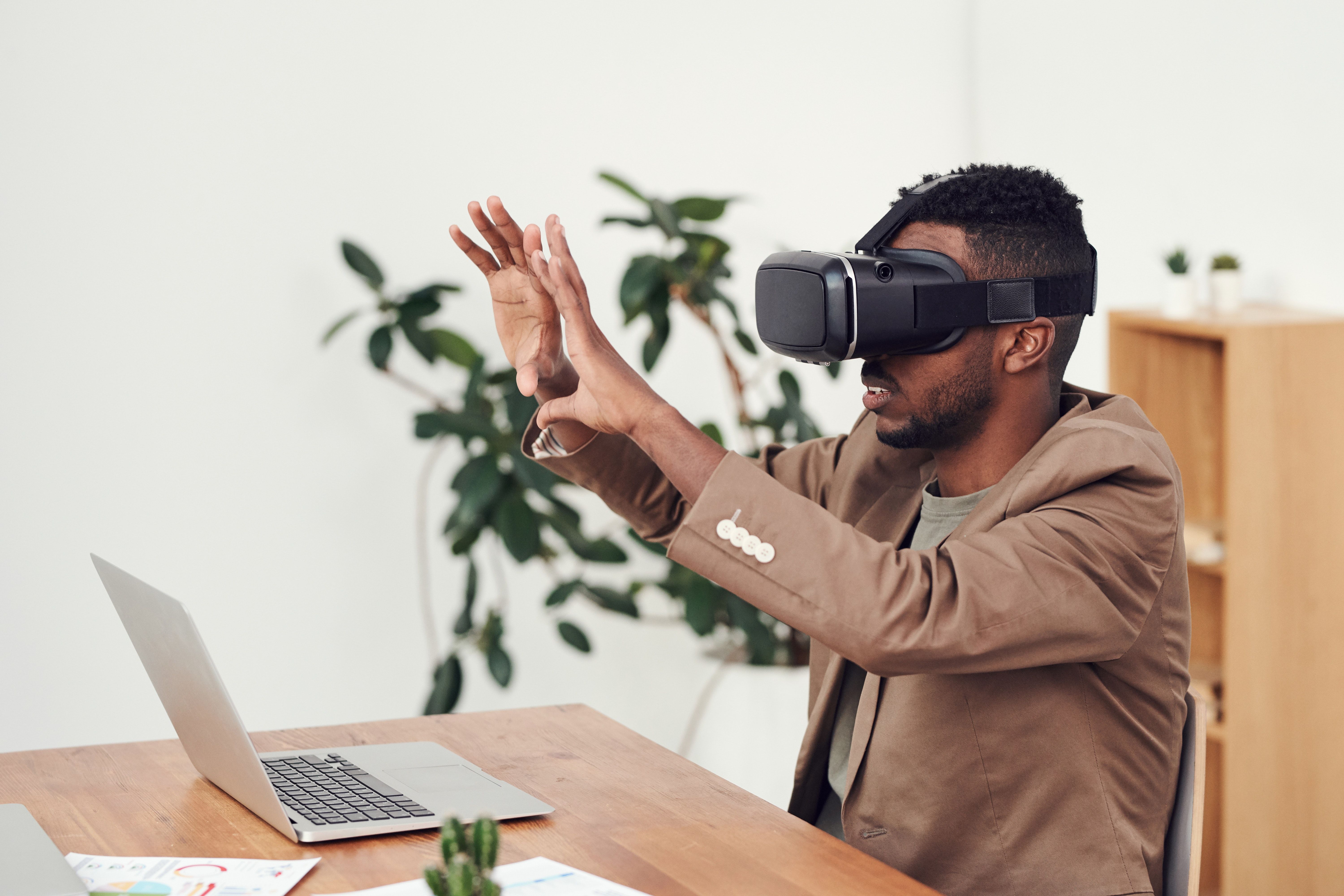 Man wearing VR headset in front of laptop.