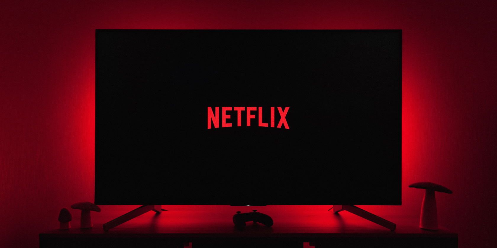 Netflix logo on large Tv screen in dark room with red backlight