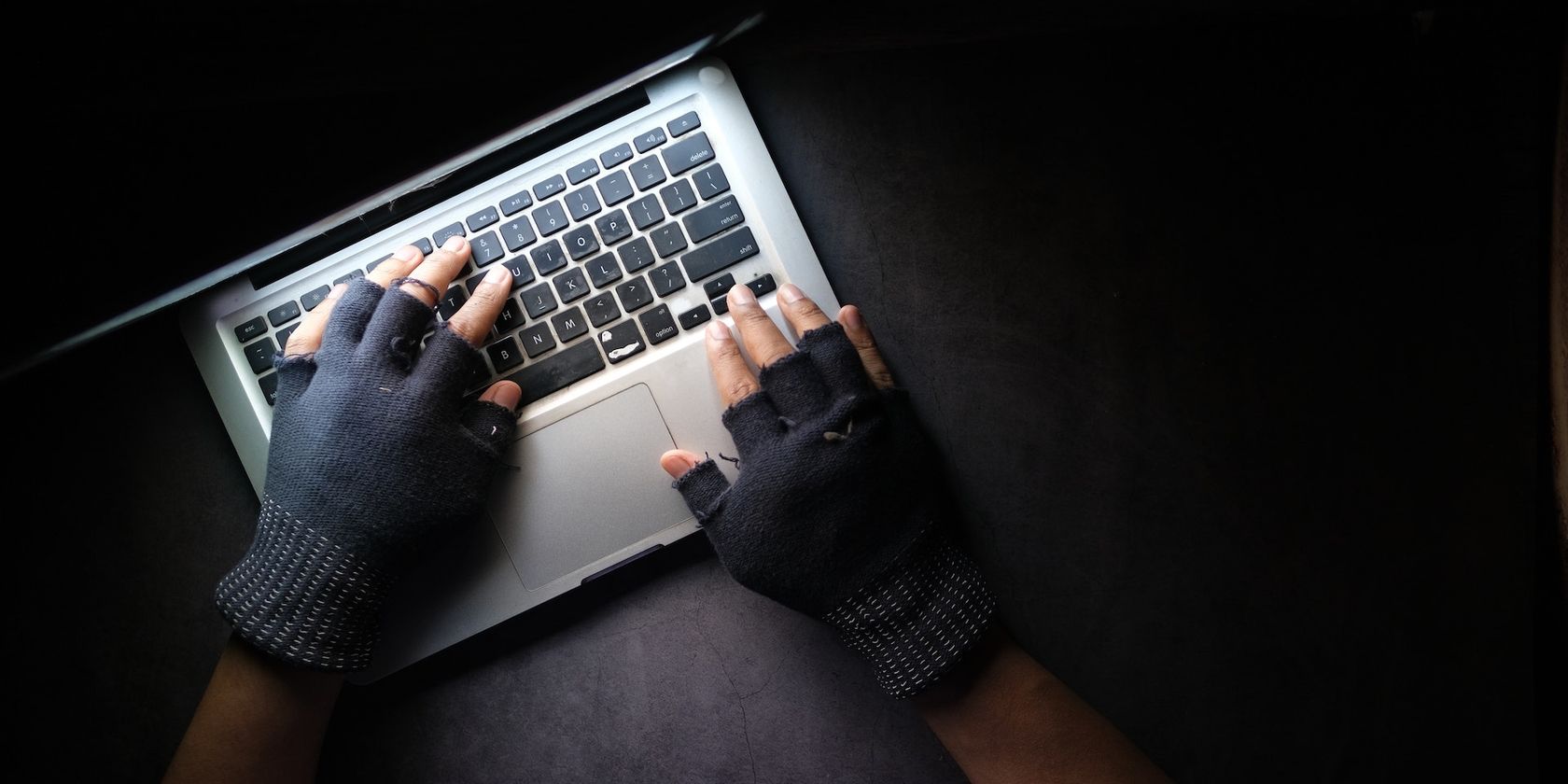 a person typing on a laptop while wearing a pair of fingerless gloves