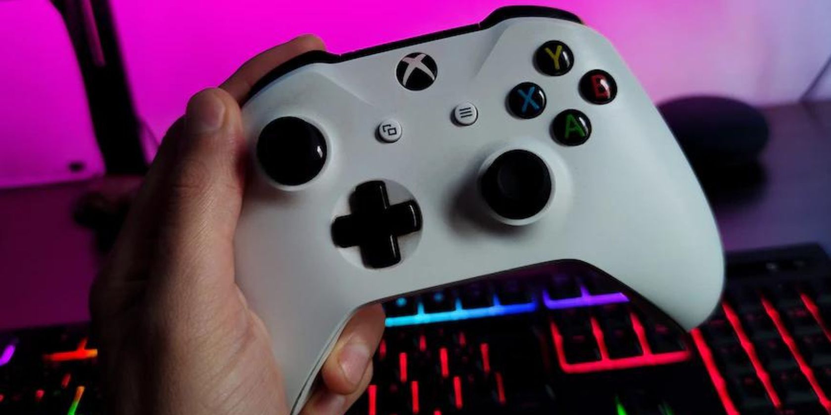 A person holding a white Xbox Series XS controller over an RPG keyboard.