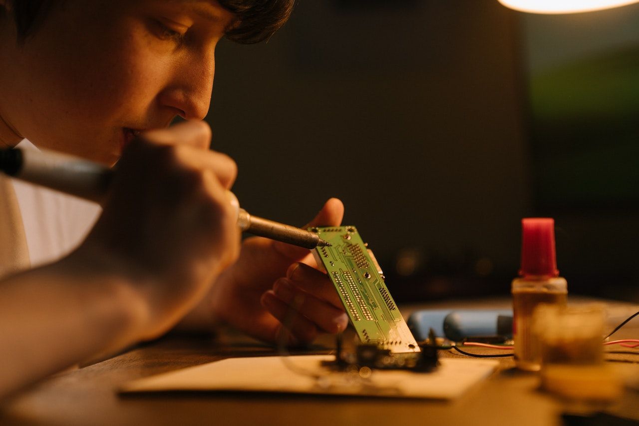 Photo of a boy soldering a circuit board