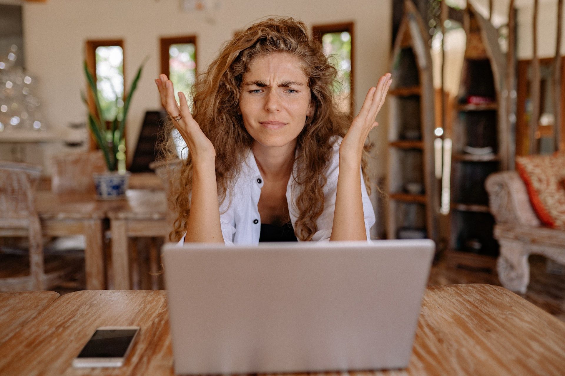 Mulher com expressão frustrada na frente do laptop