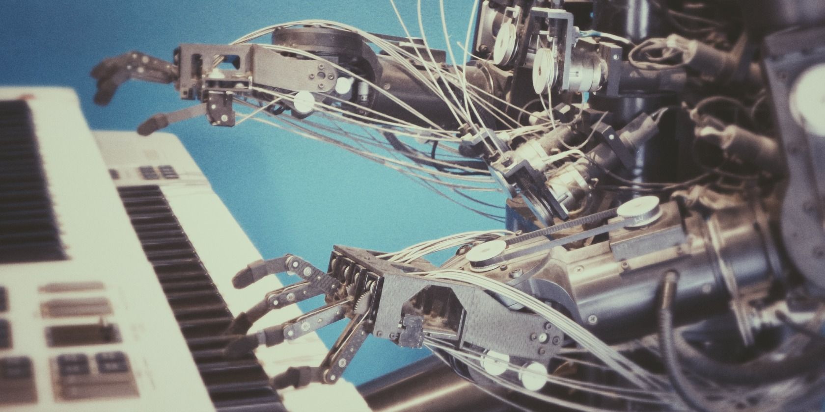 Silver robot with exposed cables playing the keyboard
