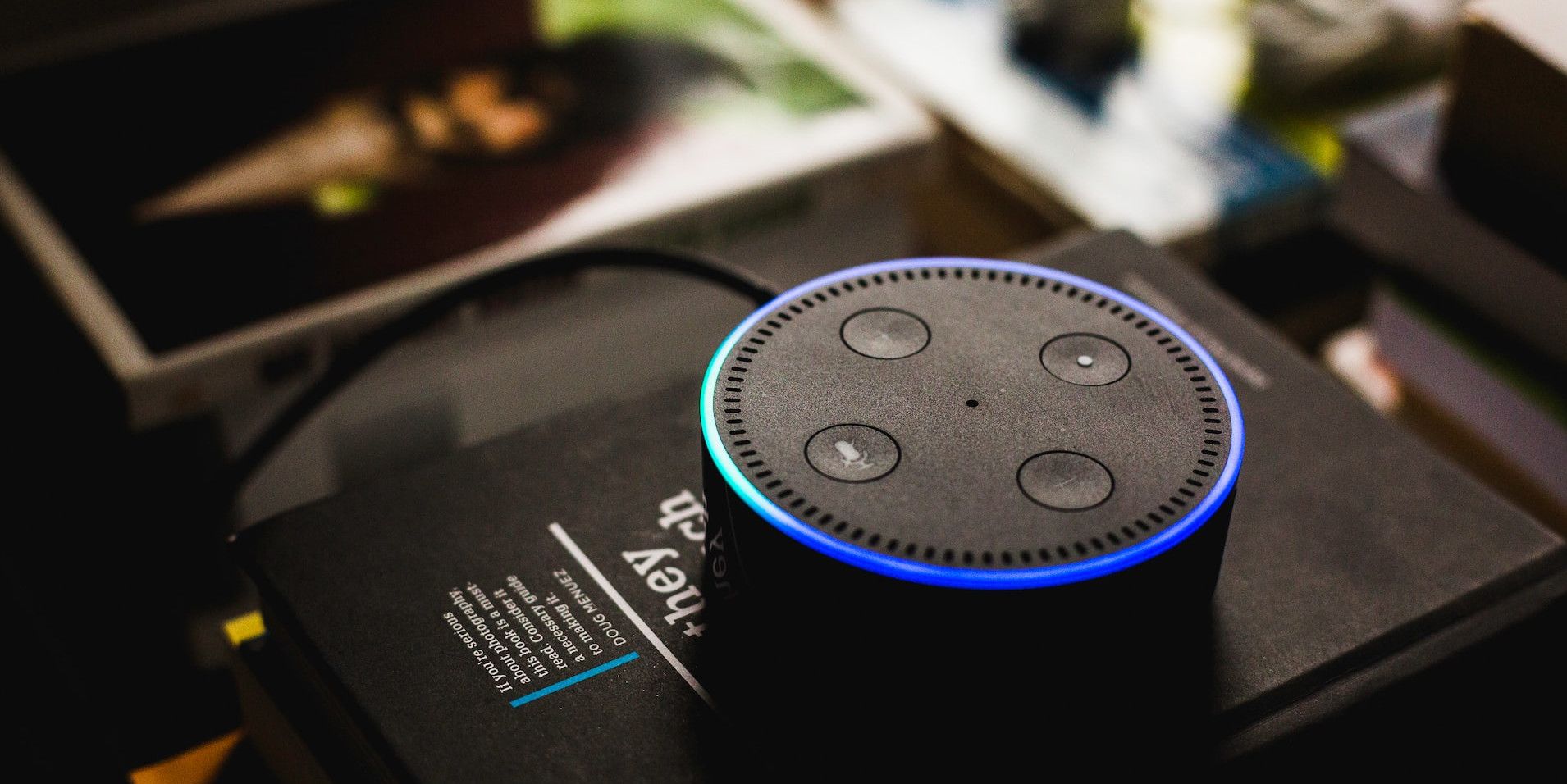 Amazon smart speaker sitting on a book with the blue listening light on 