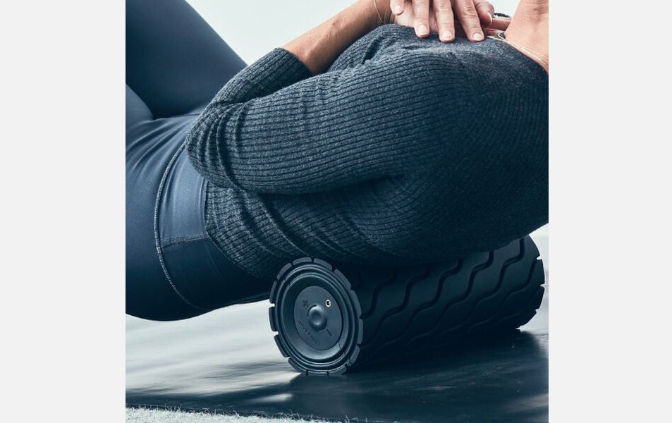Woman using the therabody foam roller on her back.