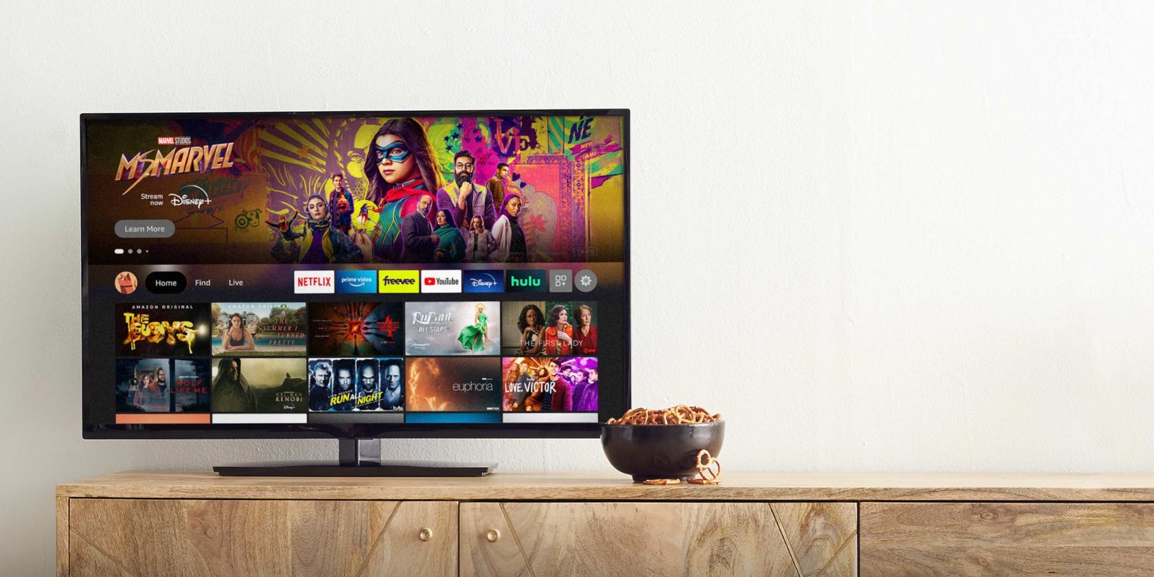 TV displaying Amazon Fire TV stick home screen with a bowl of prezels sitting to the side